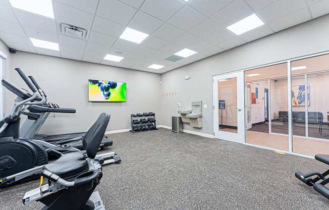 A gym room with treadmills and a television.
