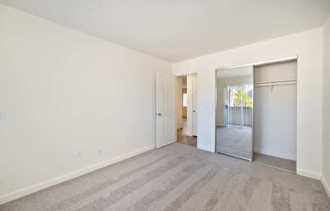 a spacious living room with carpet and a door to a bedroom