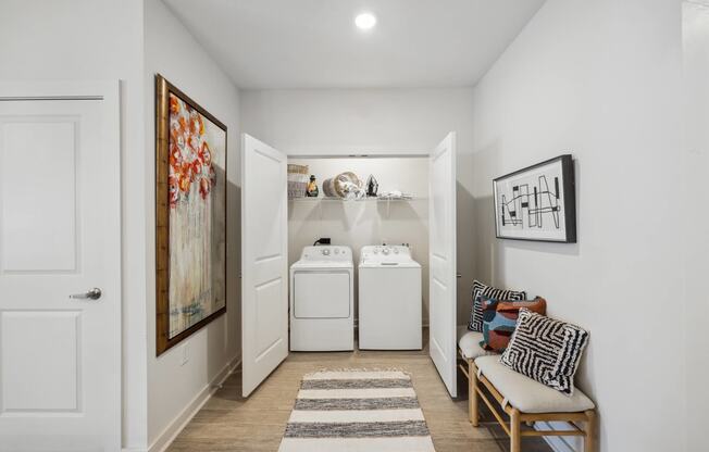 a laundry room with a washer and dryer and a chair