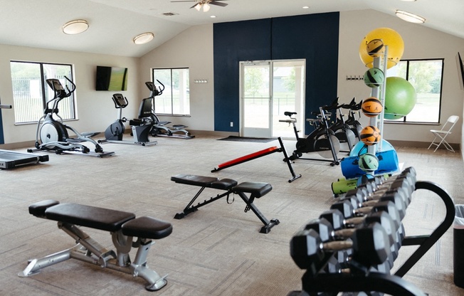 a gym with weights and other exercise equipment in a building with windows