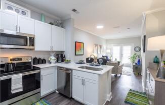 a kitchen and living room with white cabinets and stainless steel appliances