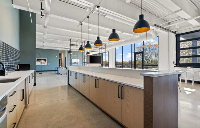 a large kitchen with a long counter and a row of hanging lights