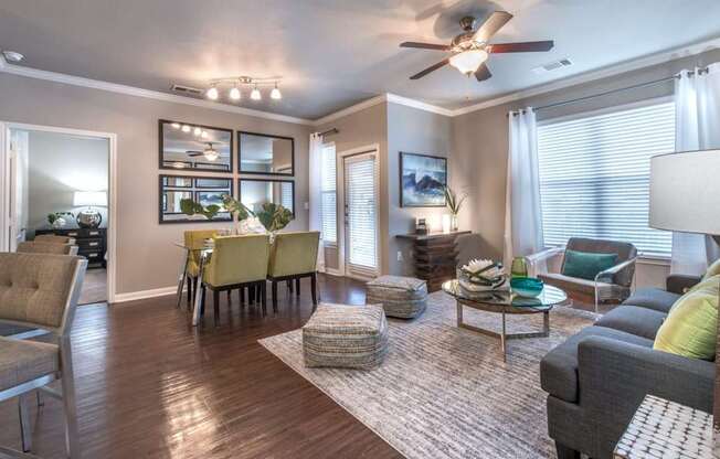 A well-lit living room with a dining area and a ceiling fan.