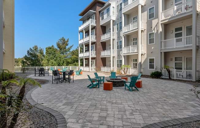 an outdoor patio with chairs and tables in front of an apartment building