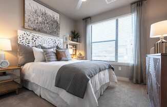 A bedroom with a large bed and a painting above it.