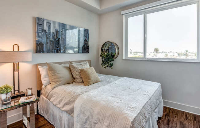A bedroom with a large bed and a cityscape painting on the wall.