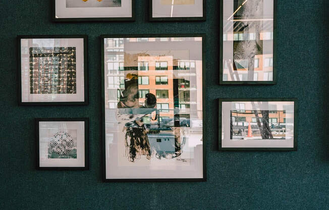 a row of pictures hanging on a wall with a green wall at The Lively, Jersey City, 07302