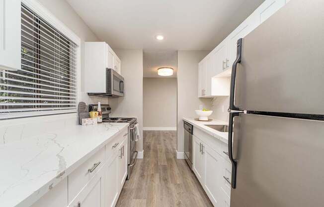 A kitchen with white cabinets and a black fridge.