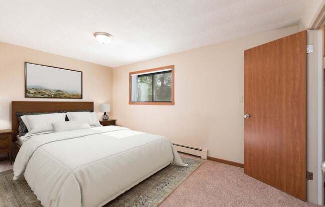 A bedroom with a large bed and a window. Bismarck, ND Parkview Arms Apartments