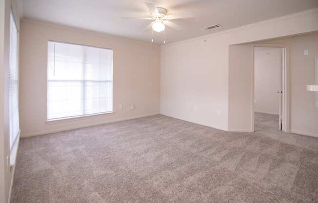 an empty living room with carpet and a ceiling fan