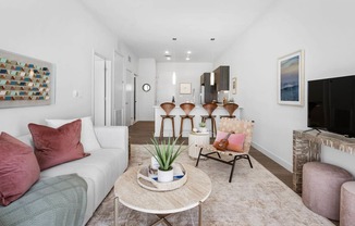 A living room with a white couch, a coffee table, and a painting on the wall.