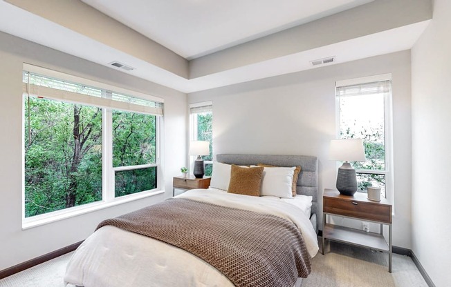 A bedroom with a large bed and a window overlooking a forest.