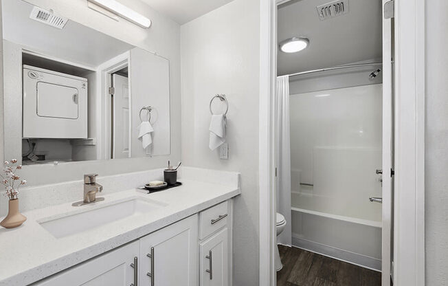 Model Bathroom with White Cabinets, Wood-Style Flooring & Shower/Tub at Crystal Creek Apartments in Phoenix, AZ.