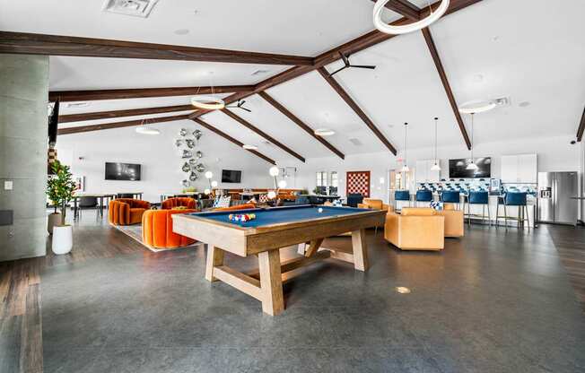 A billiard table is in the middle of a room with a concrete floor and a high ceiling.