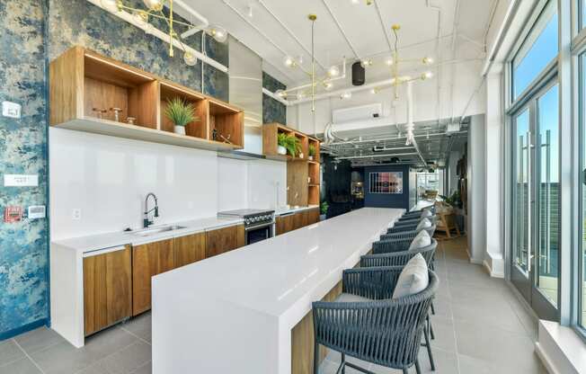 a long kitchen with a long white counter and chairs  at Link Apartments® H Street, Washington, 20002