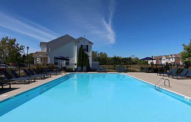 a swimming pool with chairs and a building in the background