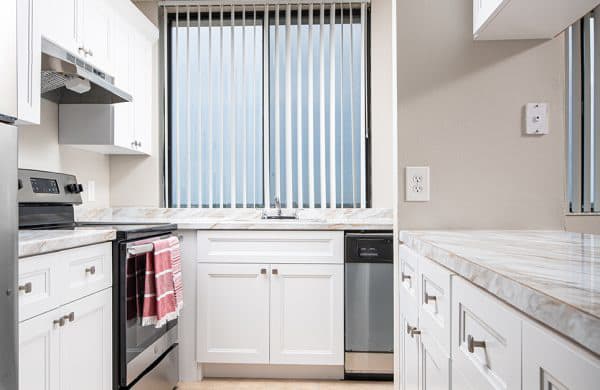 a kitchen with white cabinets and a stove and a window at Fairways of Inverrary, Lauderhill, Florida