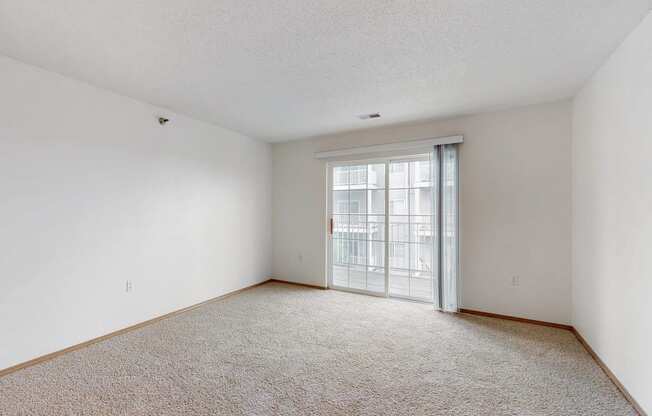 an empty living room with a door to a balcony