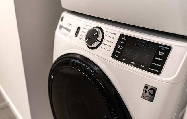modern, white laundry washing machine with black door and knobs