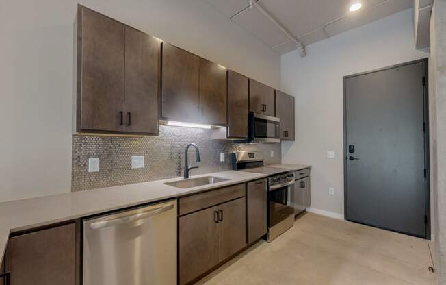 an empty kitchen with stainless steel appliances and wooden cabinets