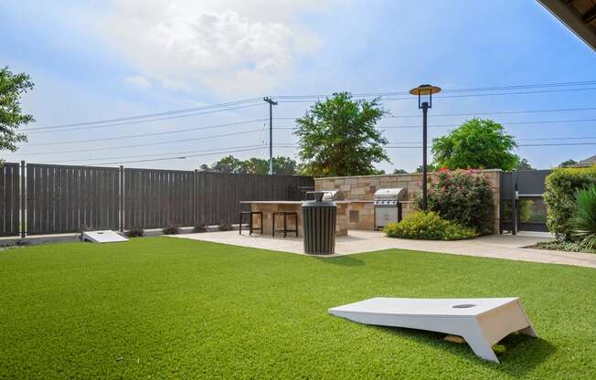 a lawn with a table and a barbecue grill in a backyard