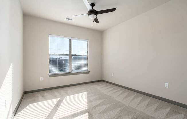 A room with a ceiling fan and a window with blinds.