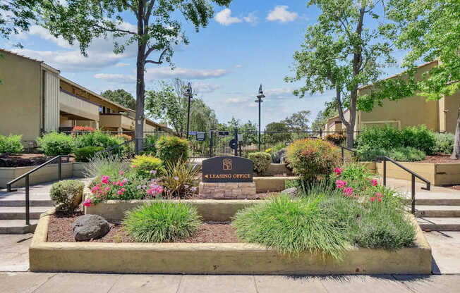 a community garden with flowers and trees and a sign at Summerwood Apartments, California