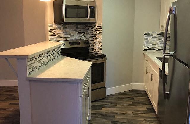 A kitchen with a white counter top and a black refrigerator.