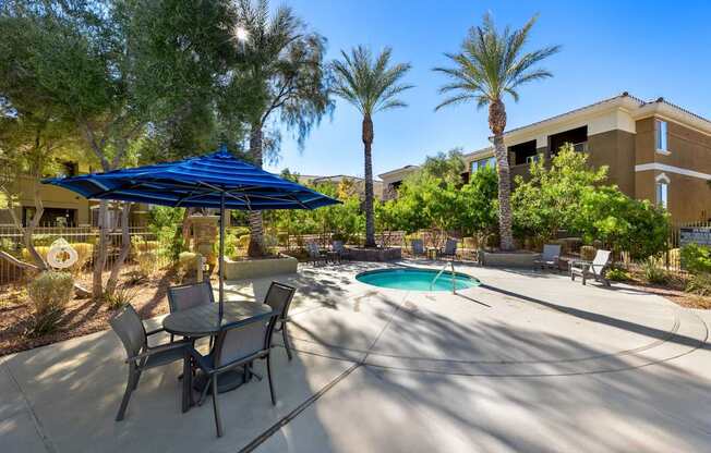 A patio with a table and chairs and a spa. at The Fairways by Picerne Apartments, Las Vegas