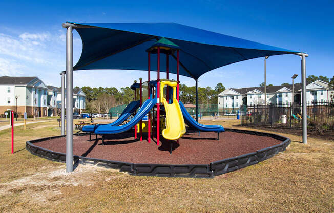 a playground with a blue canopy and yellow and blue slides