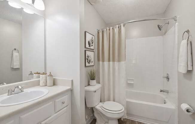 A white bathroom with a toilet, sink, and bathtub.