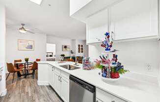 A kitchen with white cabinets and a wooden floor.