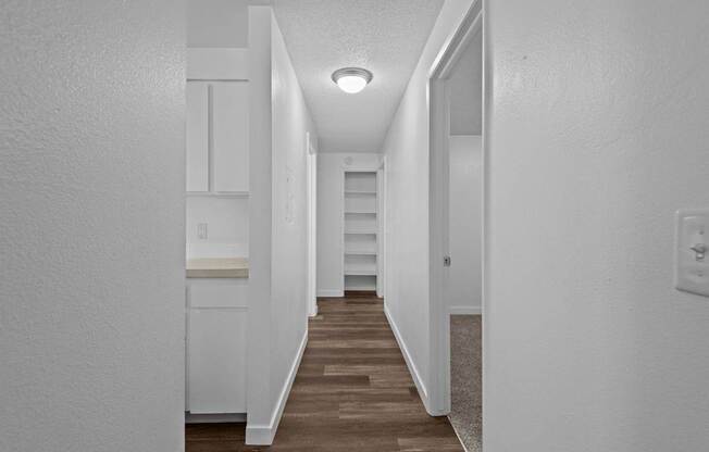 A long hallway with white walls and wood flooring.