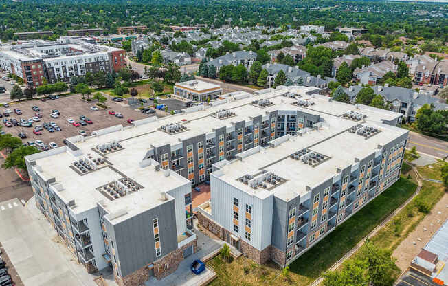 an aerial view of a large apartment building with a parking lot and a city in the background