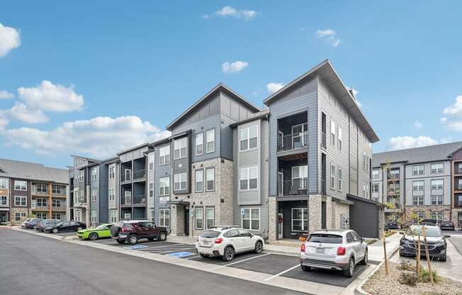 an apartment building with cars parked in a parking lot at The Quarry Luxury Apartment Homes, Fort Collins, CO