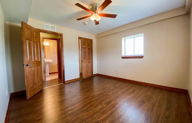 an empty bedroom with wooden floors and a ceiling fan