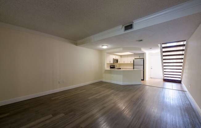 Pet-Friendly Apartments in Coconut Creek, FL – Waterview at Coconut Creek – empty living room with wood floors and a kitchen