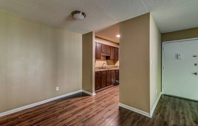 an empty living room and kitchen with wood flooring