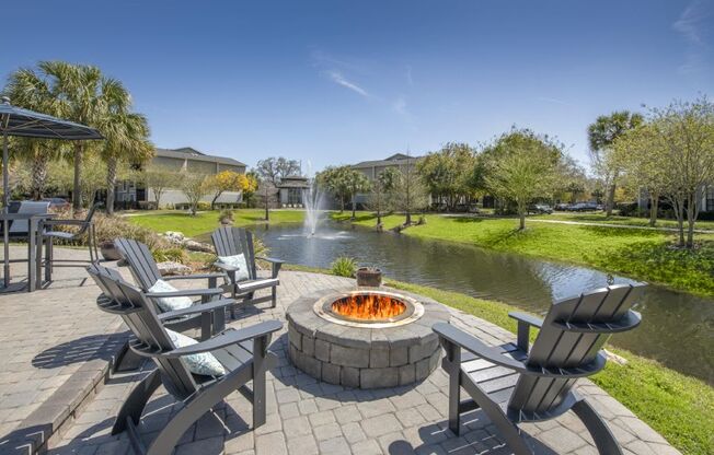 A fire pit is surrounded by chairs on a patio.