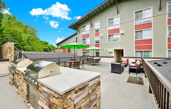 A patio with a stone barbecue and chairs.