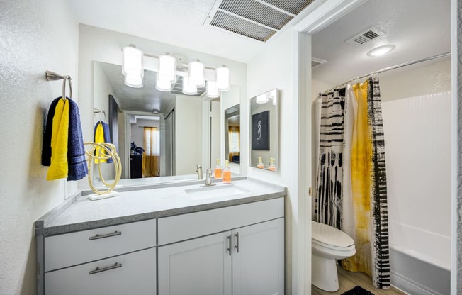 a bathroom with white cabinets and a yellow shower curtain