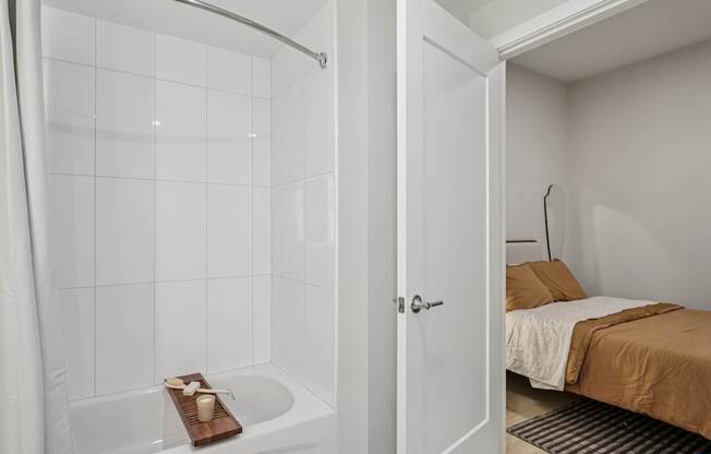 A white bathroom with a tub and a bed.