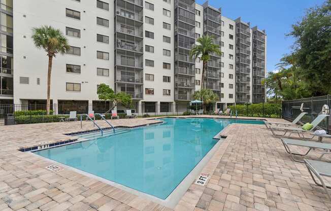 A swimming pool in front of a tall building with palm trees at Hampton Apartments, Florida, 33759