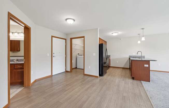 a kitchen and living room with wood flooring and a refrigerator and a sink