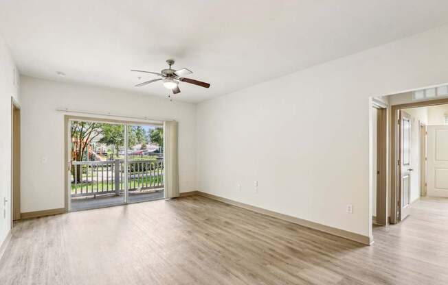 Royal Palm floor plan living room with a ceiling fan and sliding glass doors leading to a patio space at Oakleaf Plantation apartments in Jacksonville, FL.
