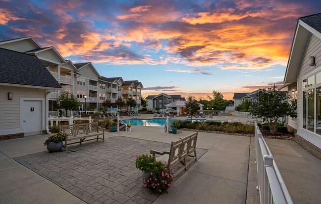 a backyard with benches and a pool at sunset