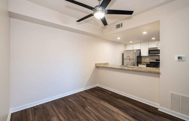 A room with a ceiling fan and wooden flooring.