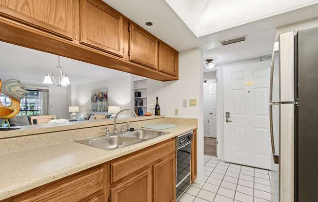 A kitchen with wooden cabinets and a black fridge at Hampton Apartments, Florida