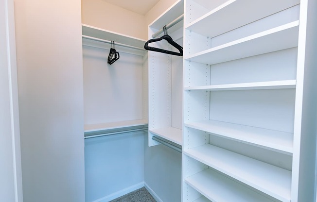 A white closet with a hanger and shelves.