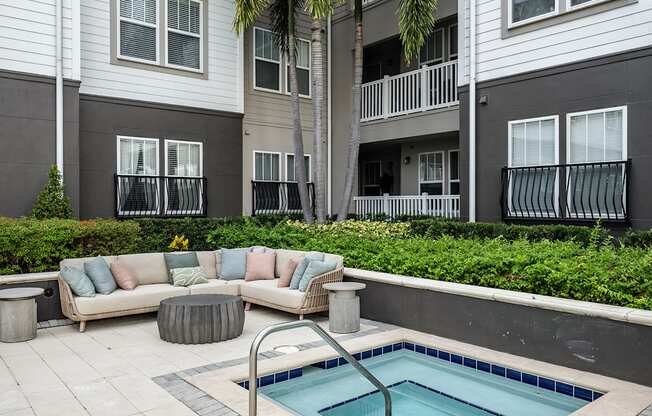 A pool in a backyard with a couch and a table.